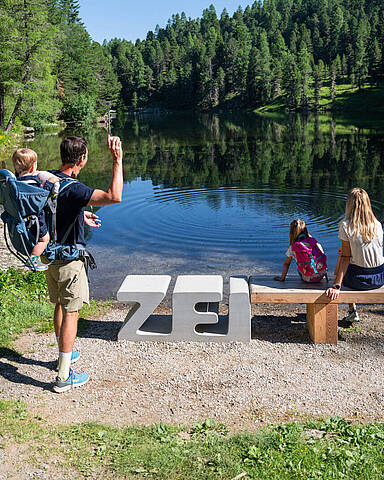 Familie erlebt den ZEITPlatz Die Ringe der ZEIT am Grünsee auf der Turracher Höhe mit Steinwurf ins Wasser