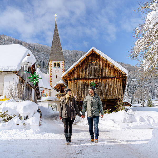 Pärchen spaziert vor einer Hütte im Schnee in Bad Kleinkirchheim