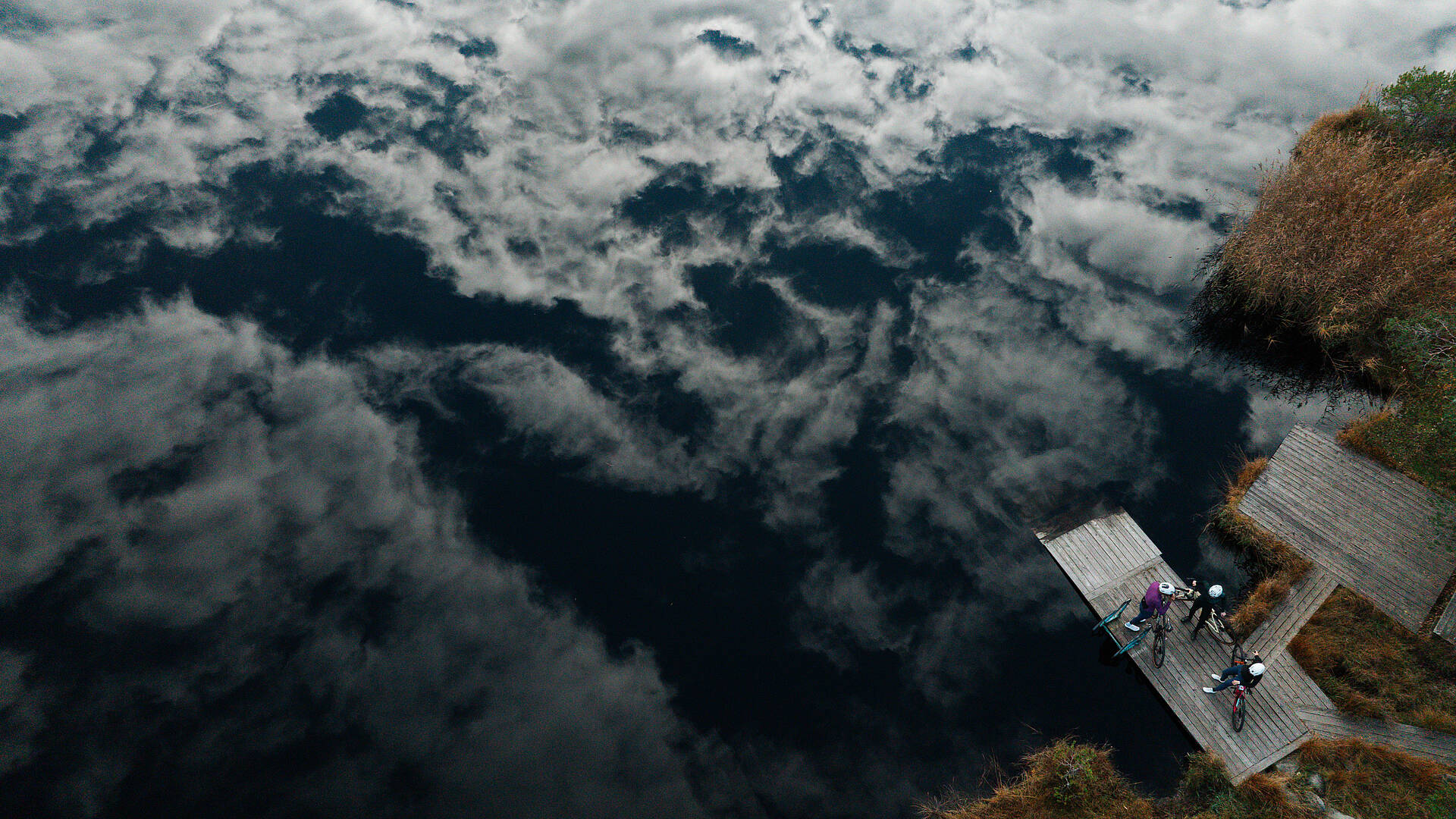3 Radfahrer stehen auf Steg am Egelsee mit Gravelbike