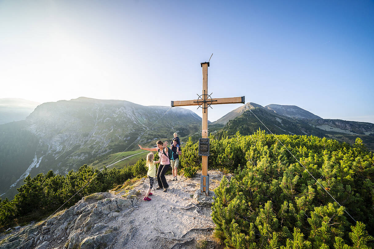 Familien hat Erfolgserlebnis bei Gipfelkreuz, da sie zusammen den 1. Gipfel in den Nockbergen bewältigt haben.