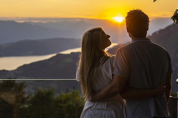 Pärchen steht am Sternenbalkon und genießt den Sonnenuntergang mit einer Aussicht über den Millstätter See