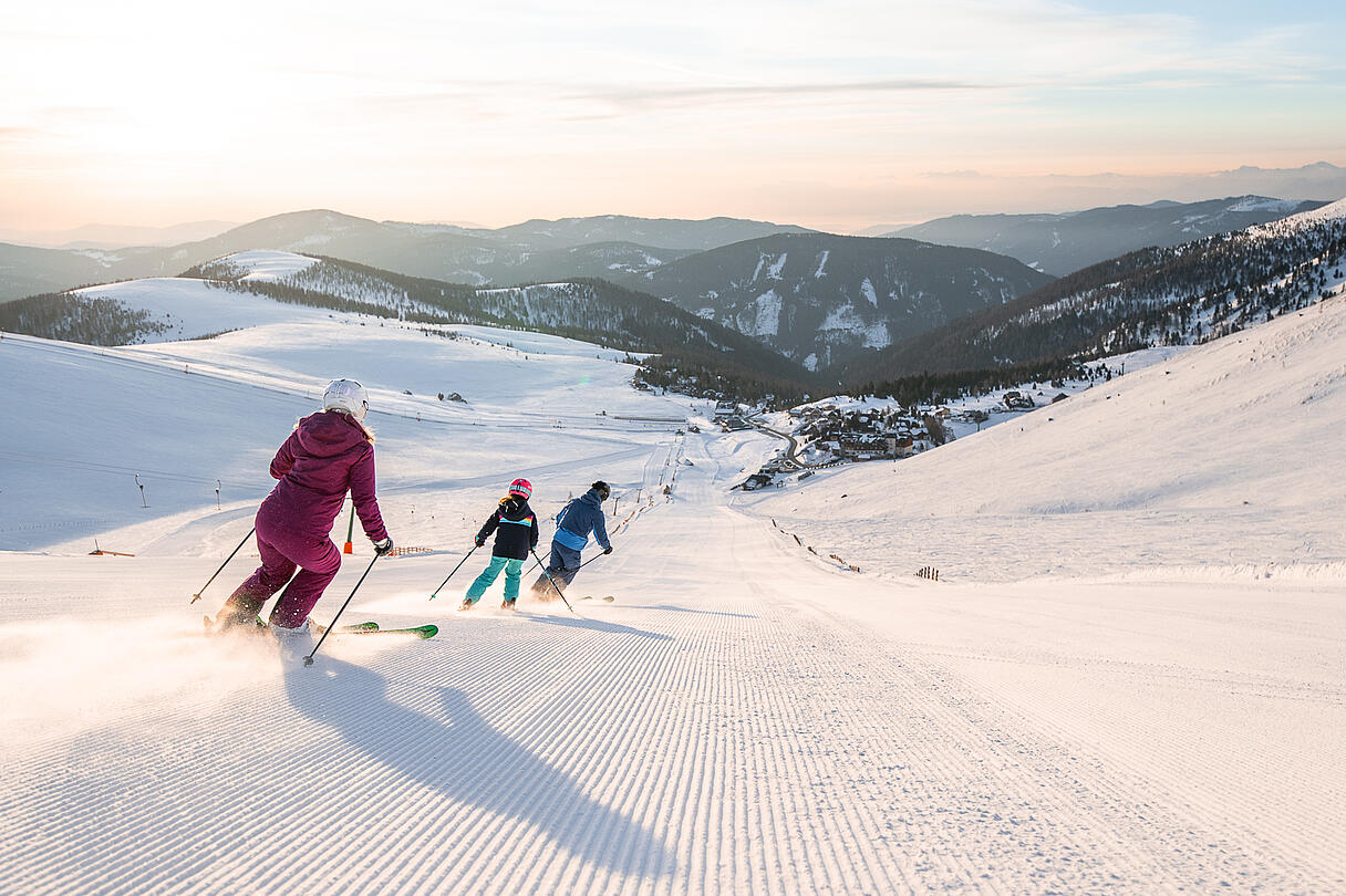 Familie fährt zusammen eine Piste am Falkert hinunter