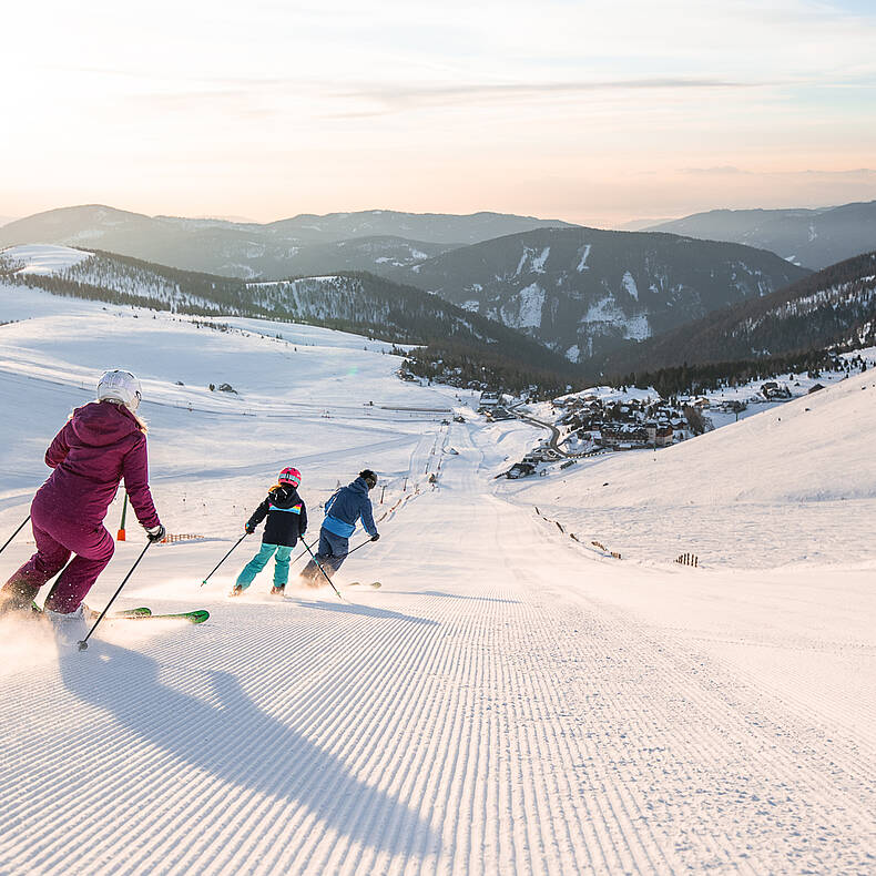 Familie fährt zusammen eine Piste am Falkert hinunter