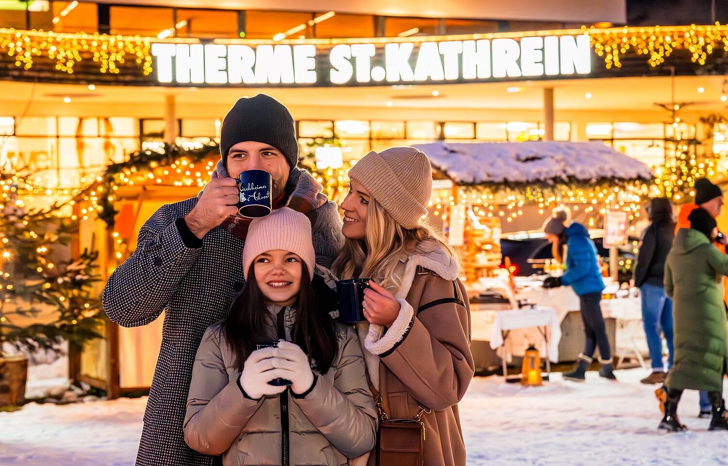 Glückliche Familie steht am Kirchheimer Adventmarkt und trinkt ein ein heißes Getränk