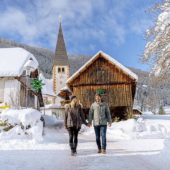 Pärchen spaziert vor einer Hütte im Schnee in Bad Kleinkirchheim