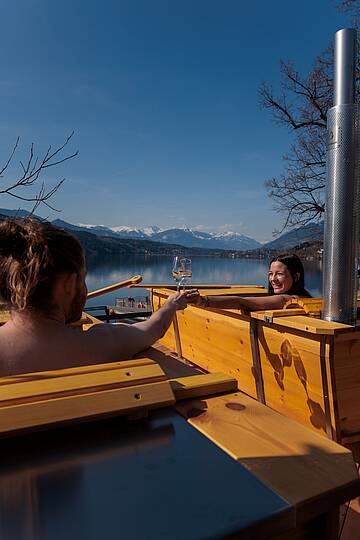 Pärchen entspannt in einer Outdoor-Badewanne direkt am Millstätter See mit Bergblick