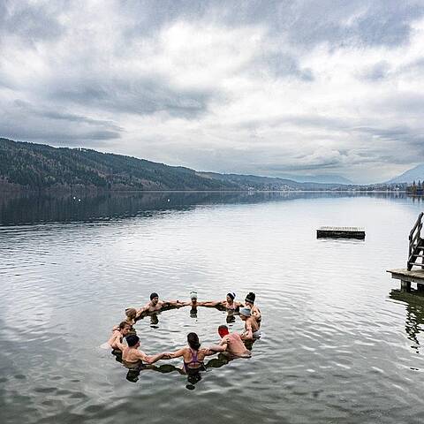 Personen bilden einen Kreis im Millstätter See beim Kaltbadeworkshhop