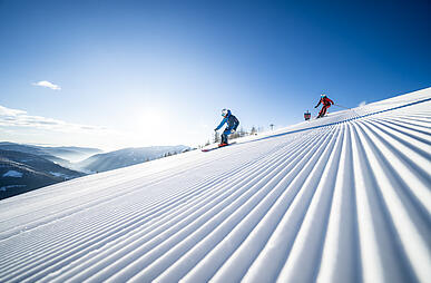 Skifahrer fahren die frisch präparierte Piste in Bad Kleinkirchheim hinunter