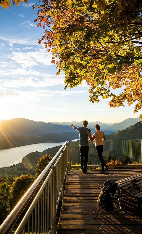 Pärchen steht am Sternenbalkon im Herbst mit Blick auf den Millstätter See