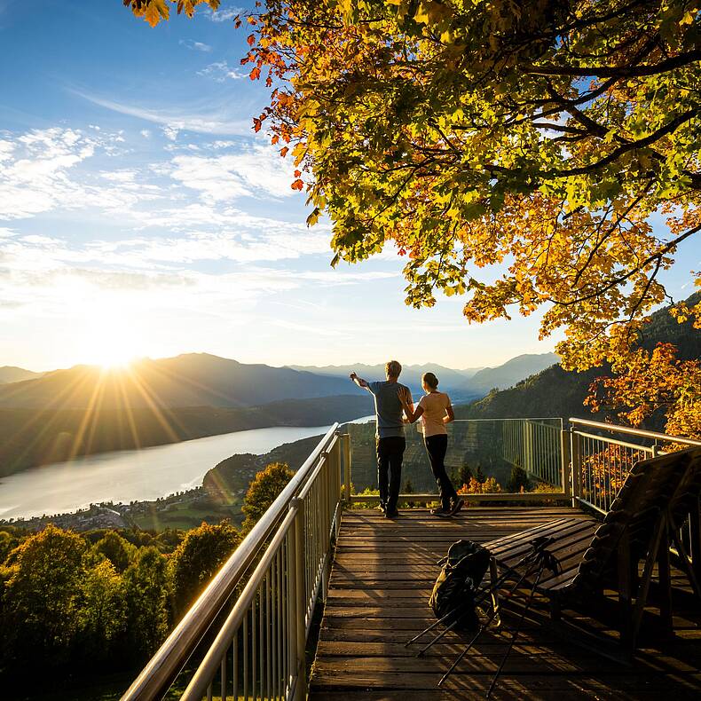 Pärchen steht am Sternenbalkon im Herbst mit Blick auf den Millstätter See