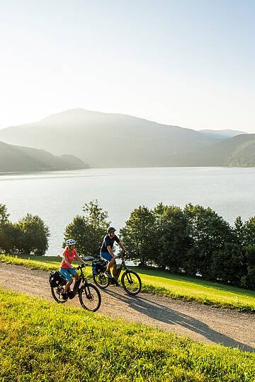 2 Personen fahren mit ihren Rädern den Radweg um den Millstätter See entlang